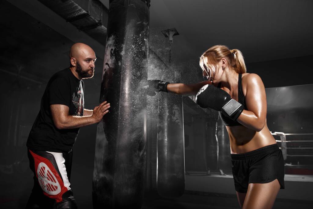 a woman using a punching bag which is a custom boxing equipment