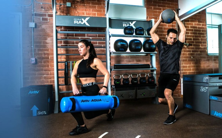 A woman and a man at a fitness centre working out with functional fitness equipment.