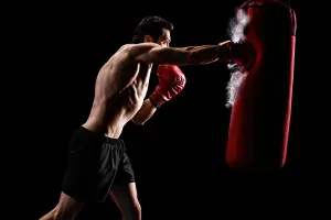 A man on hitting a punch bag for boxing.