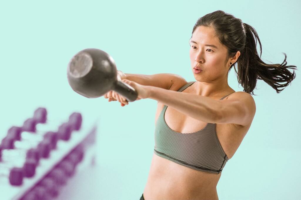 A woman doing a kettlebell swing workout intending to reap kettlebell benefits