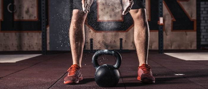 Close up pf an athlete's legs with a kettle bell, reaping kettlebell benefits