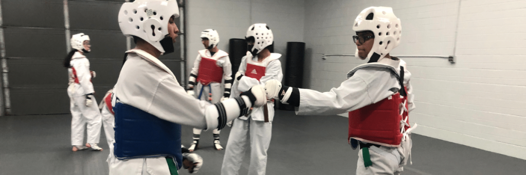 Atheletes practising taekwondo weaing TKD